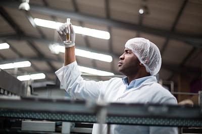 Factory engineers checking a sample of drink in drinks production plant