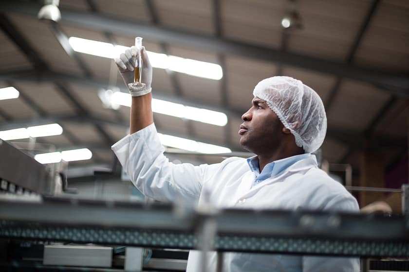 Factory engineers checking a sample of drink in drinks production plant