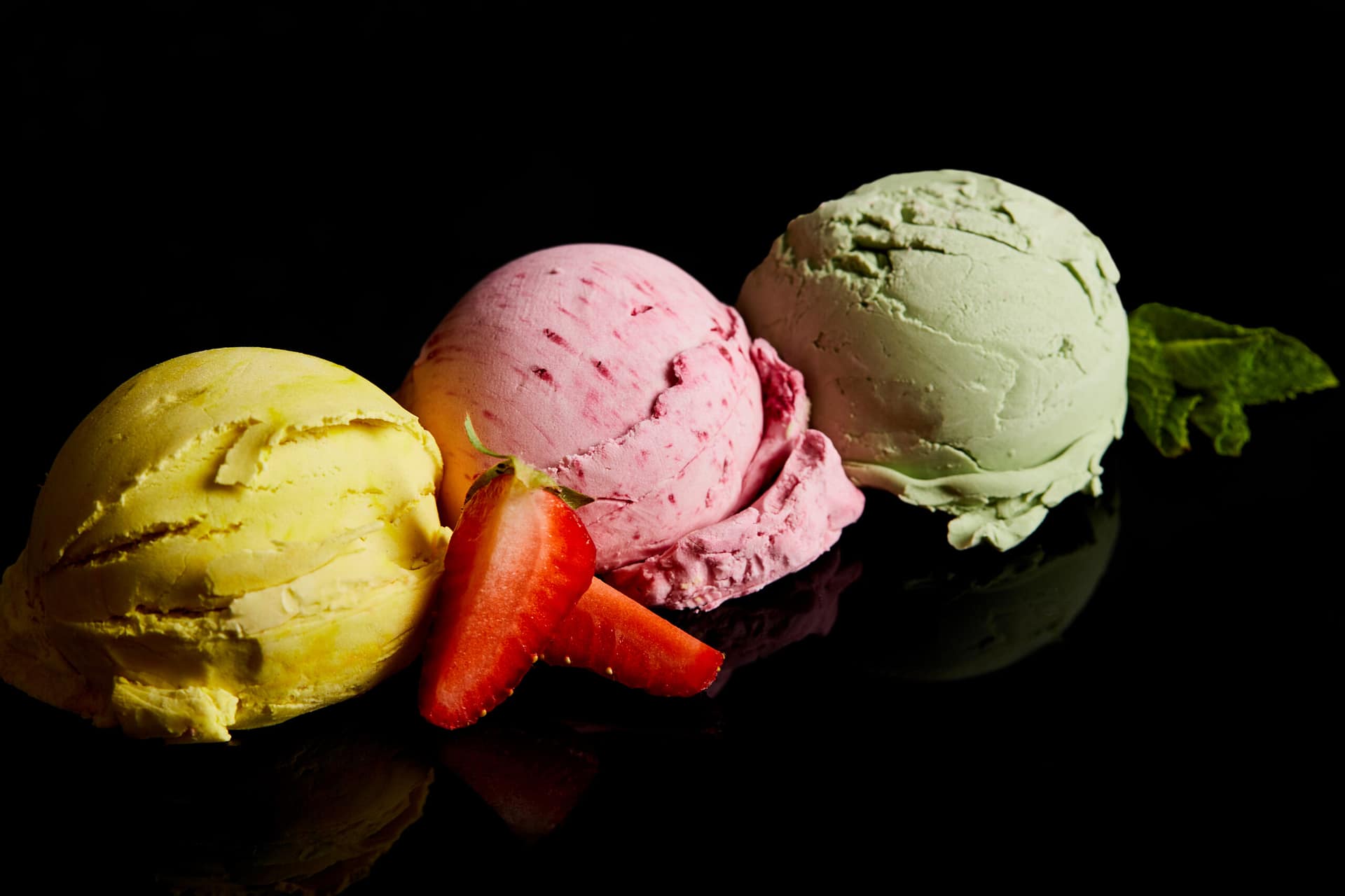 delicious lemon, strawberry and mint ice cream balls isolated on black