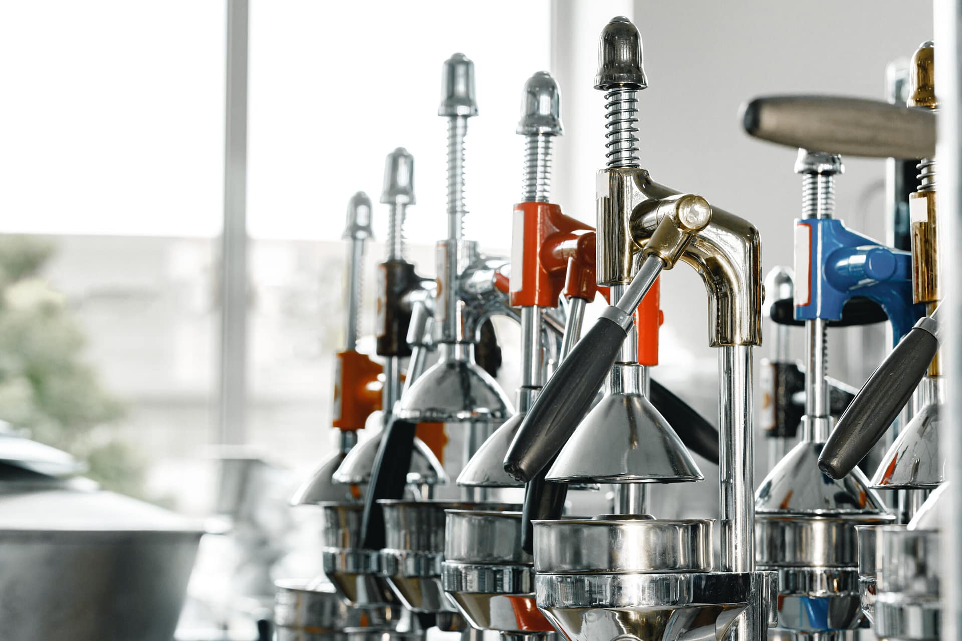 New metal manual juicers in a row on shop shelf close up