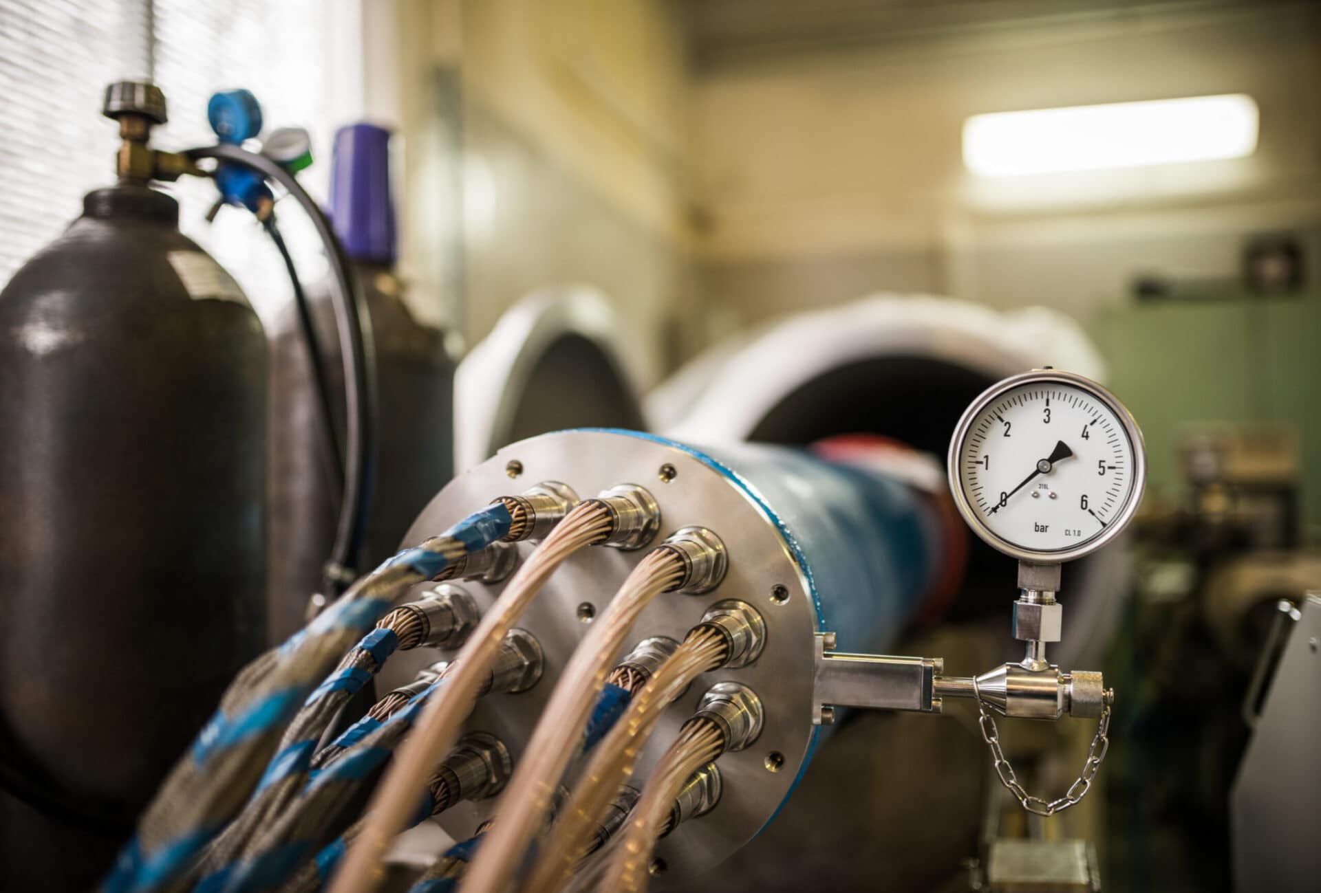 A set of high voltage cables in common nozzle worn on iron drum with barometer connected to it